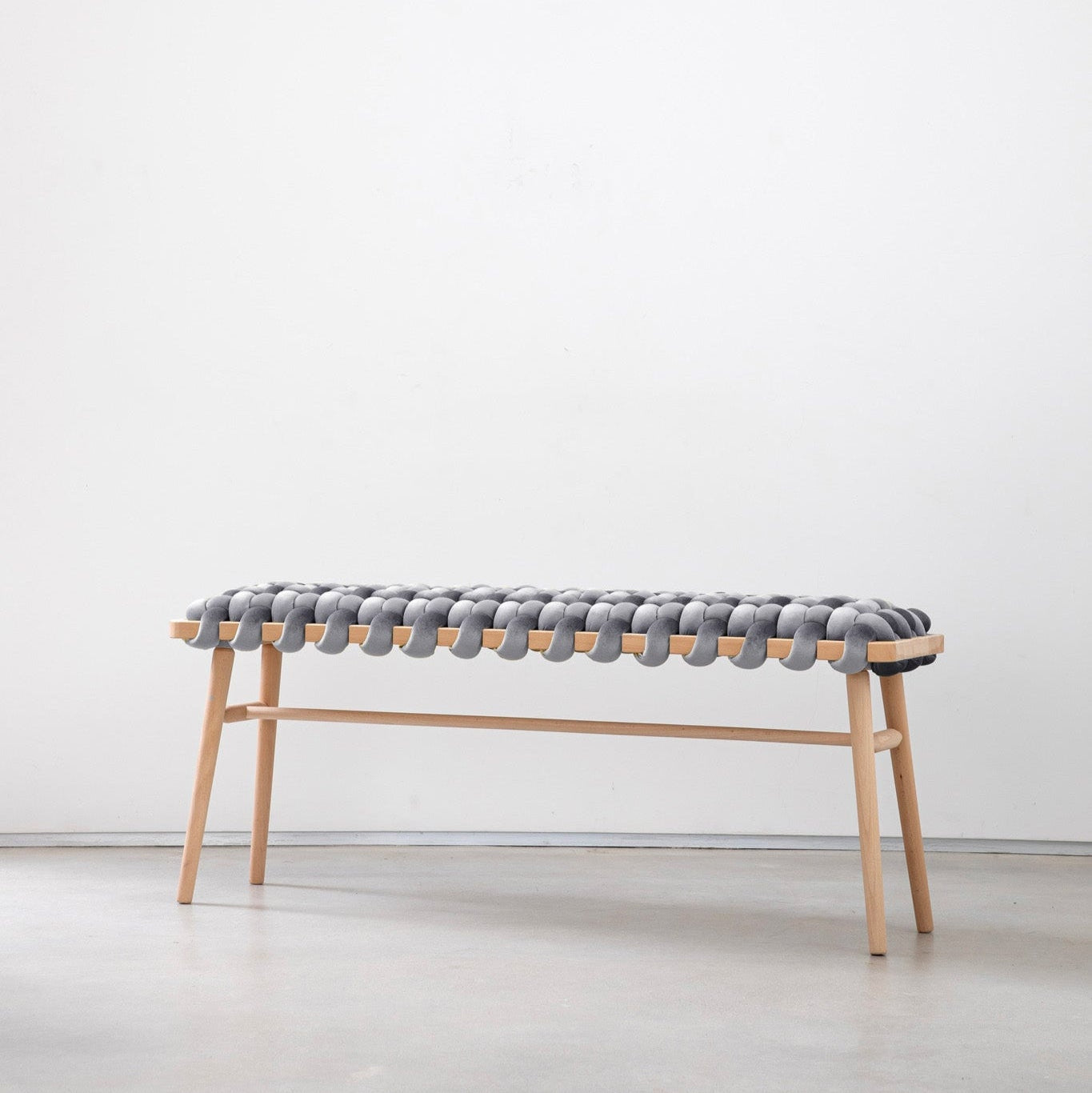 A gray velvet woven bench with a wooden frame, likely beechwood, placed against a white background.
