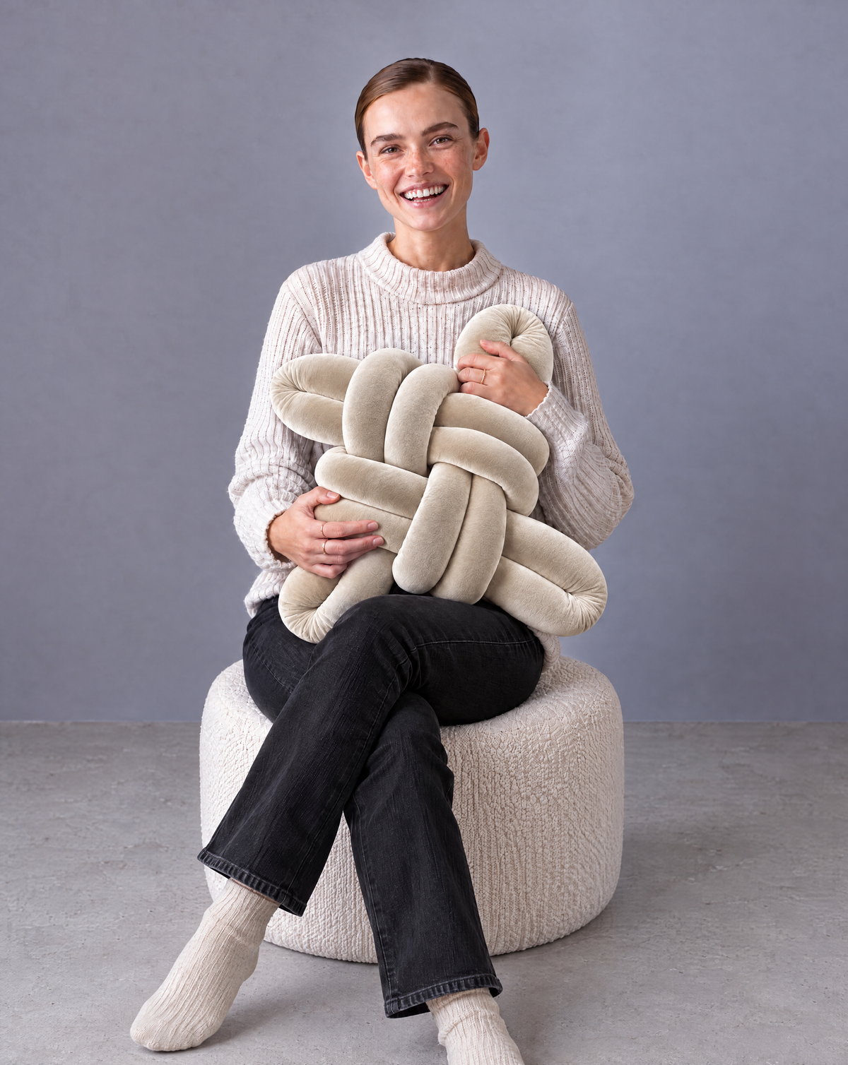 Smiling woman holding a pearl velvet knot pillow