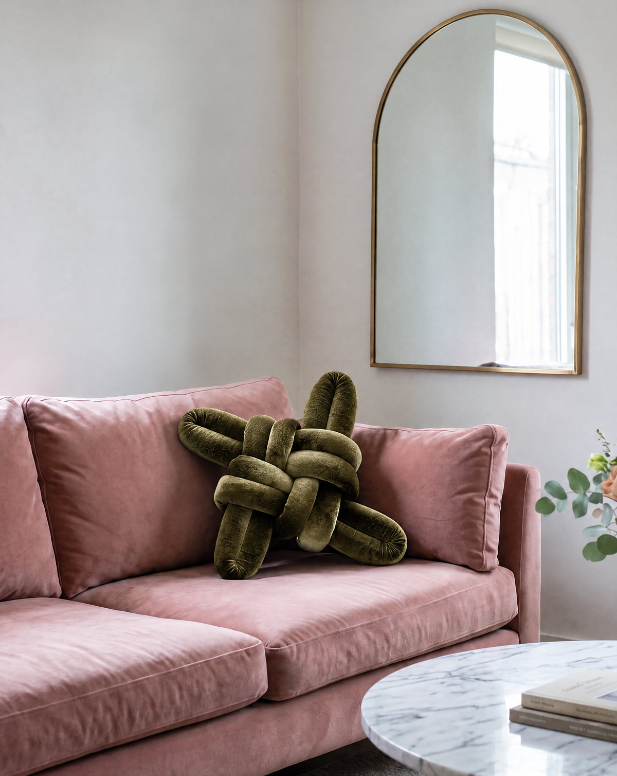 Olive green velvet knot pillow on a pink velvet sofa