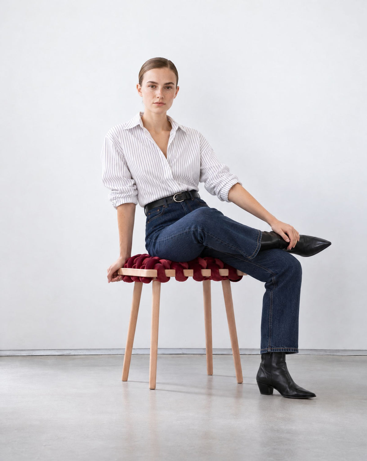 Woman sitting on a burgundy velvet woven stool