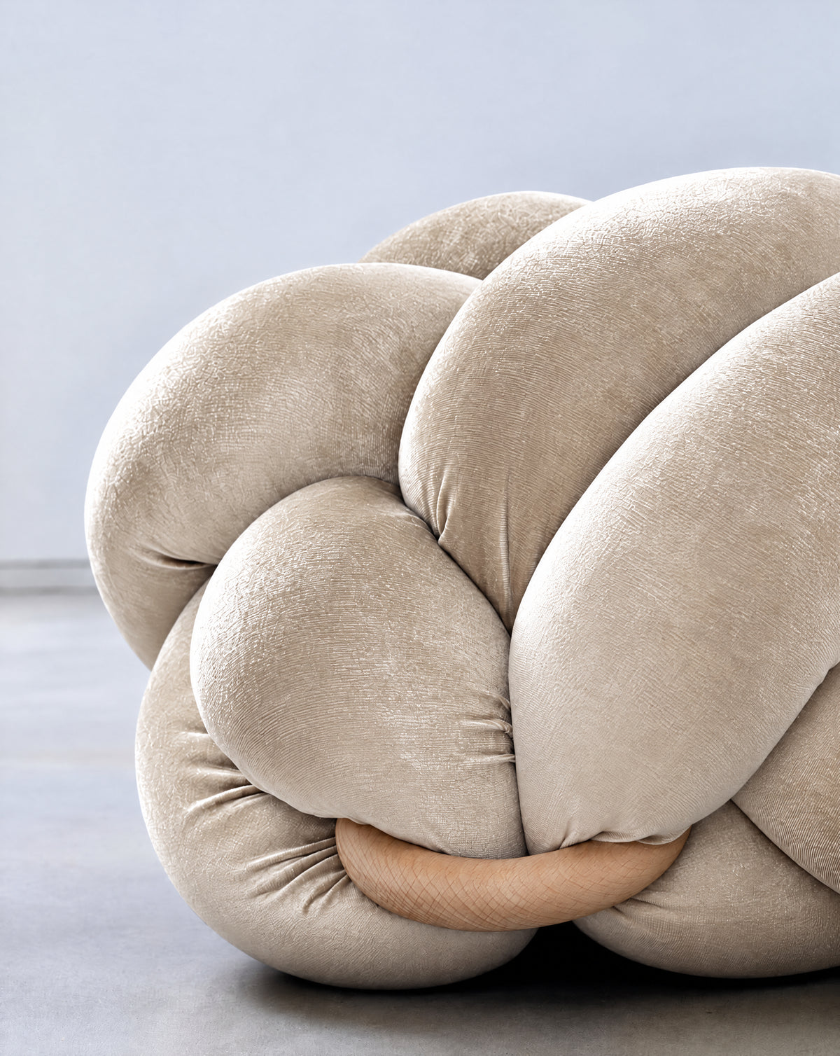 Close-up of a pearl velvet knot ottoman with its wooden ring
