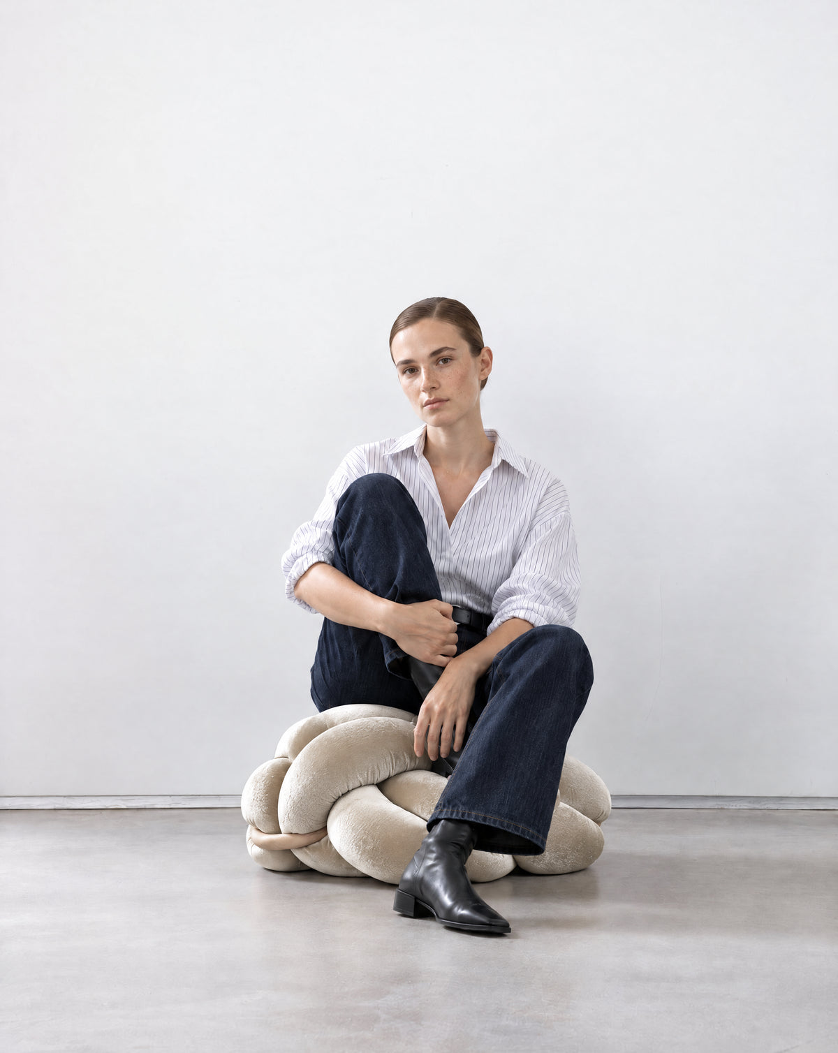 Woman sitting on a pearl velvet knot ottoman