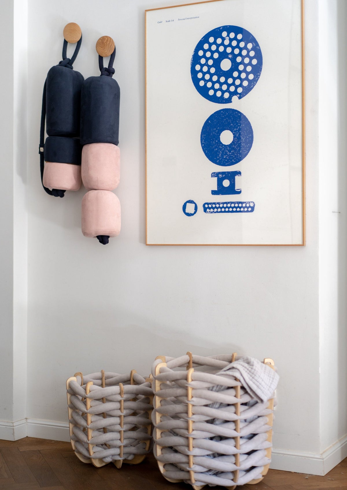 Buoy cushions hanging on a wall next to a framed poster and baskets