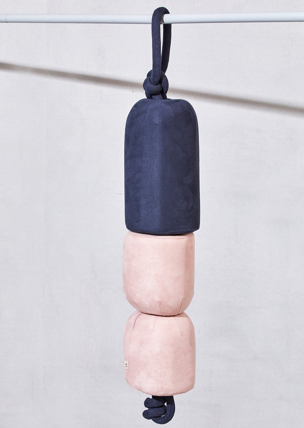 Diver's Buoy cushion in navy and pink, hanging from a rope