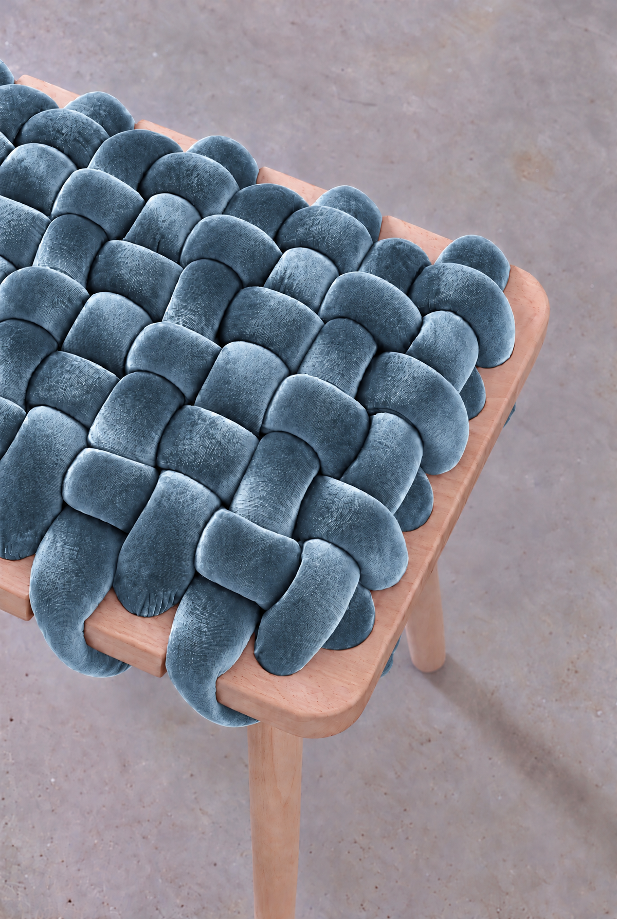 Close-up of the ocean blue velvet weave on the woven bench's beechwood frame