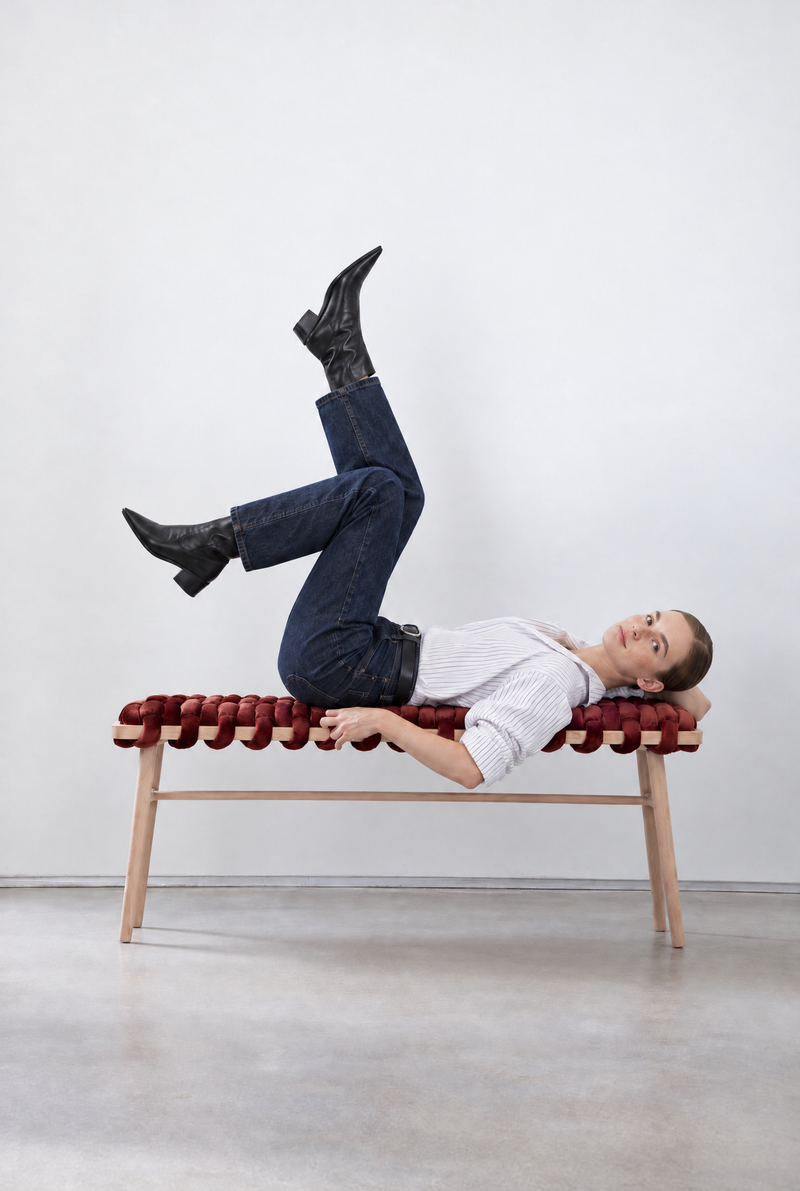 Woman lying on a 47 inch maroon velvet woven bench with her legs up