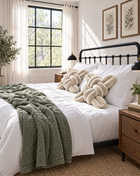Two pearl velvet knot pillows on a bed with a green throw