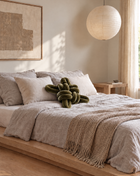 Olive green velvet knot pillow on a linen bed