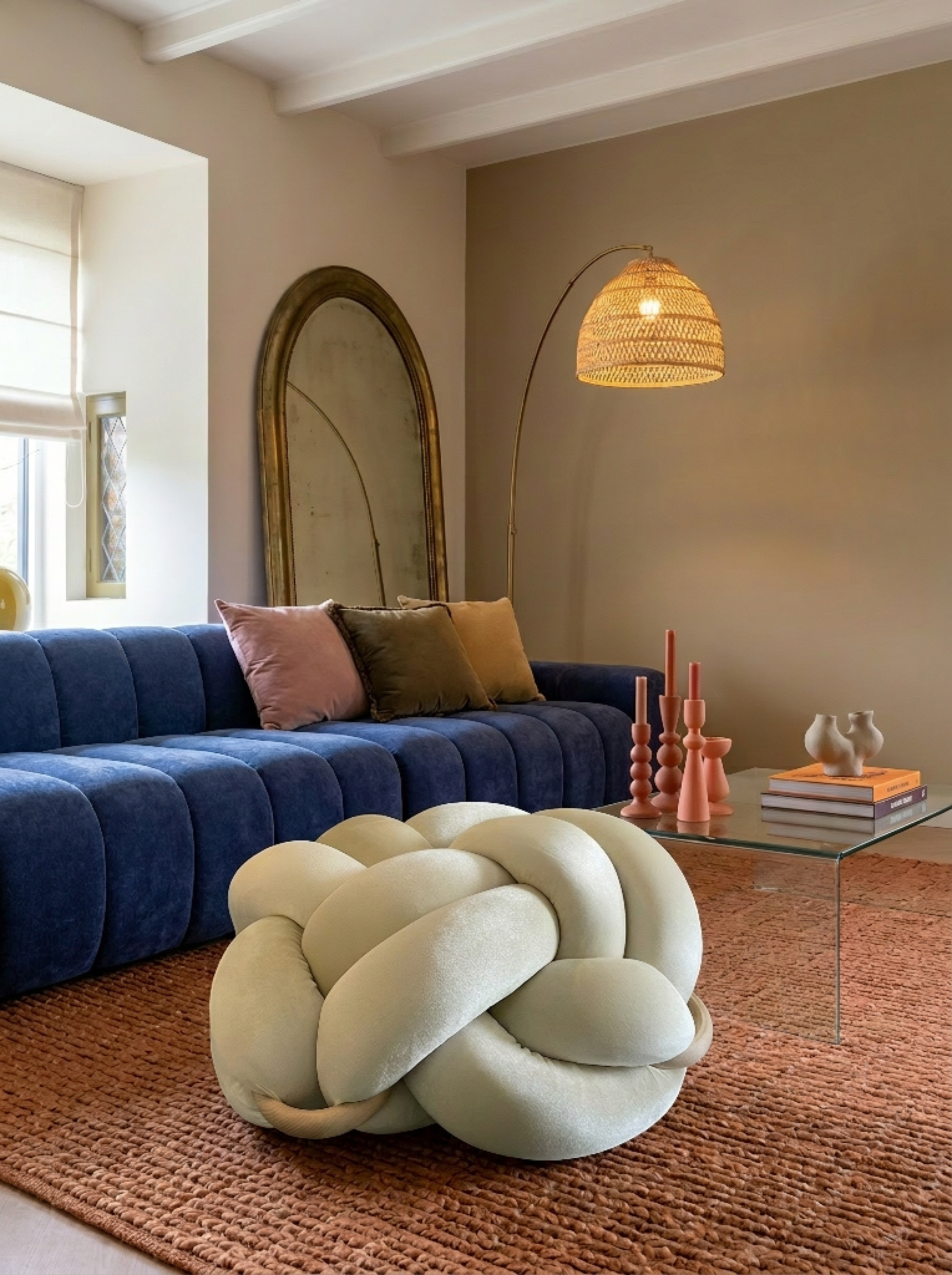 Modern living room with a blue sofa, knot-shaped pillow, and decorative items.
