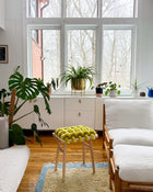 Modern living room with white furniture, plants, and a large window.