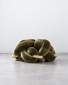 Large olive green velvet knot ottoman on a grey floor