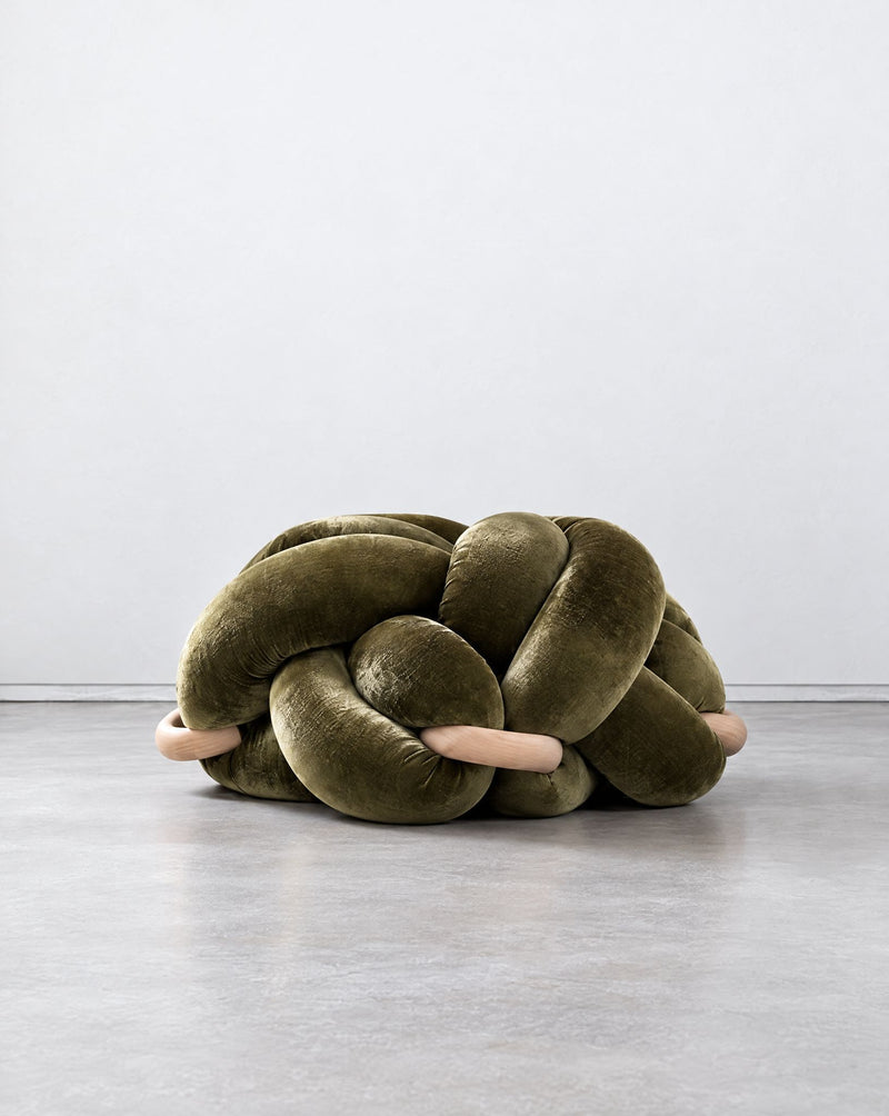 Large olive green velvet knot ottoman on a grey floor