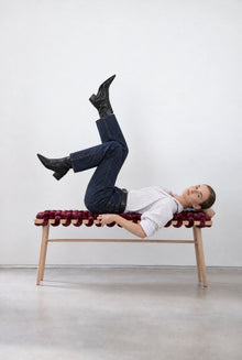 Woman lounging on a 47 inch burgundy velvet woven bench