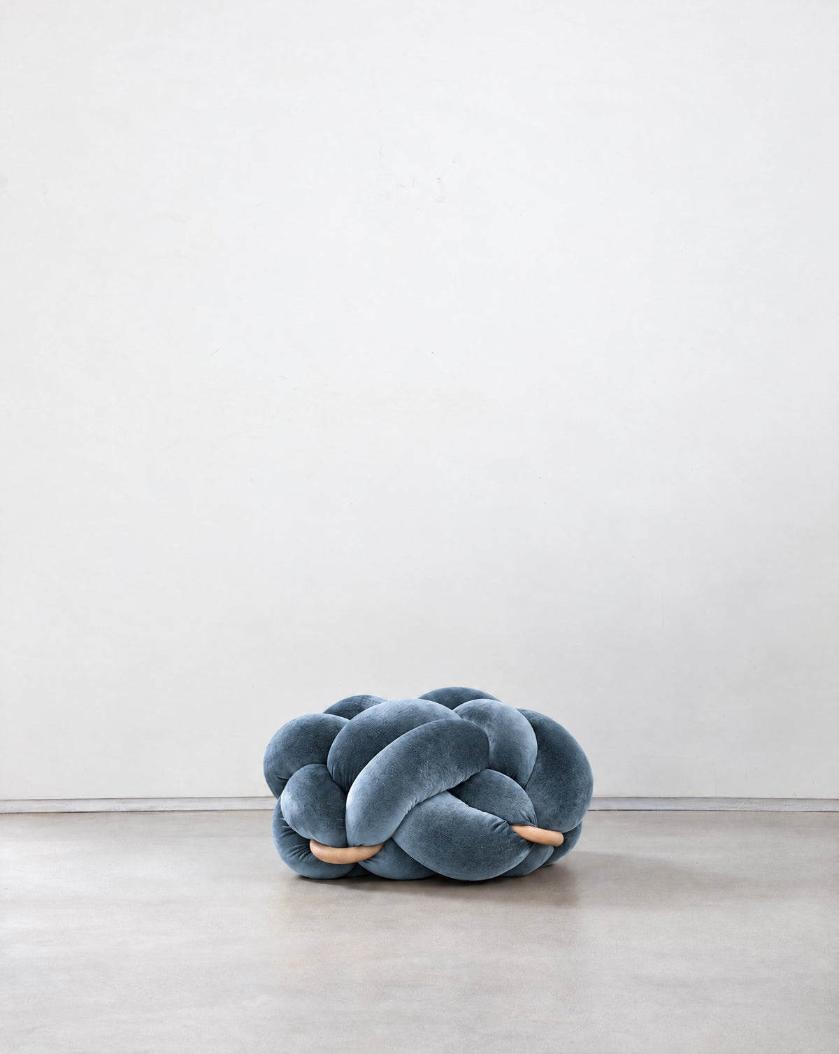 Ocean blue velvet knot ottoman on a concrete floor