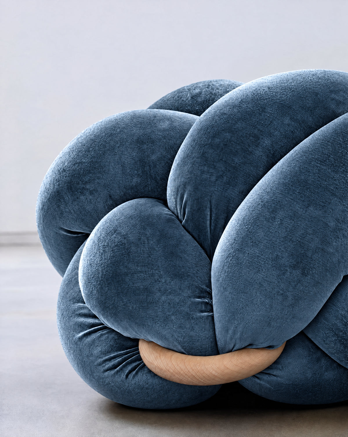 Close-up of an ocean blue velvet knot ottoman with its wooden ring