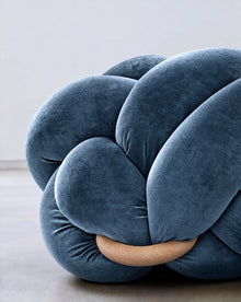 Close-up of an ocean blue velvet knot ottoman with its wooden ring
