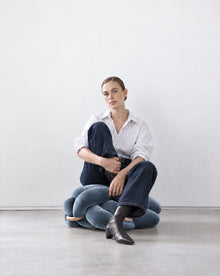 Woman sitting on an ocean blue velvet knot ottoman