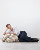 Woman lying on the floor leaning on a pearl velvet knot ottoman