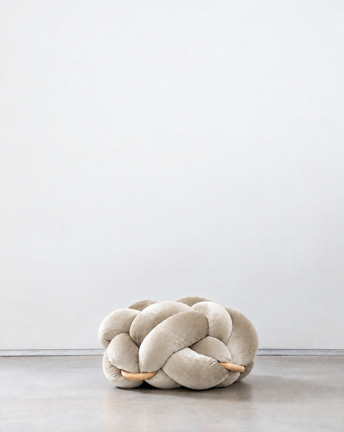 Pearl velvet knot ottoman on a concrete floor
