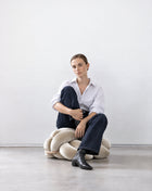Woman sitting on a pearl velvet knot ottoman
