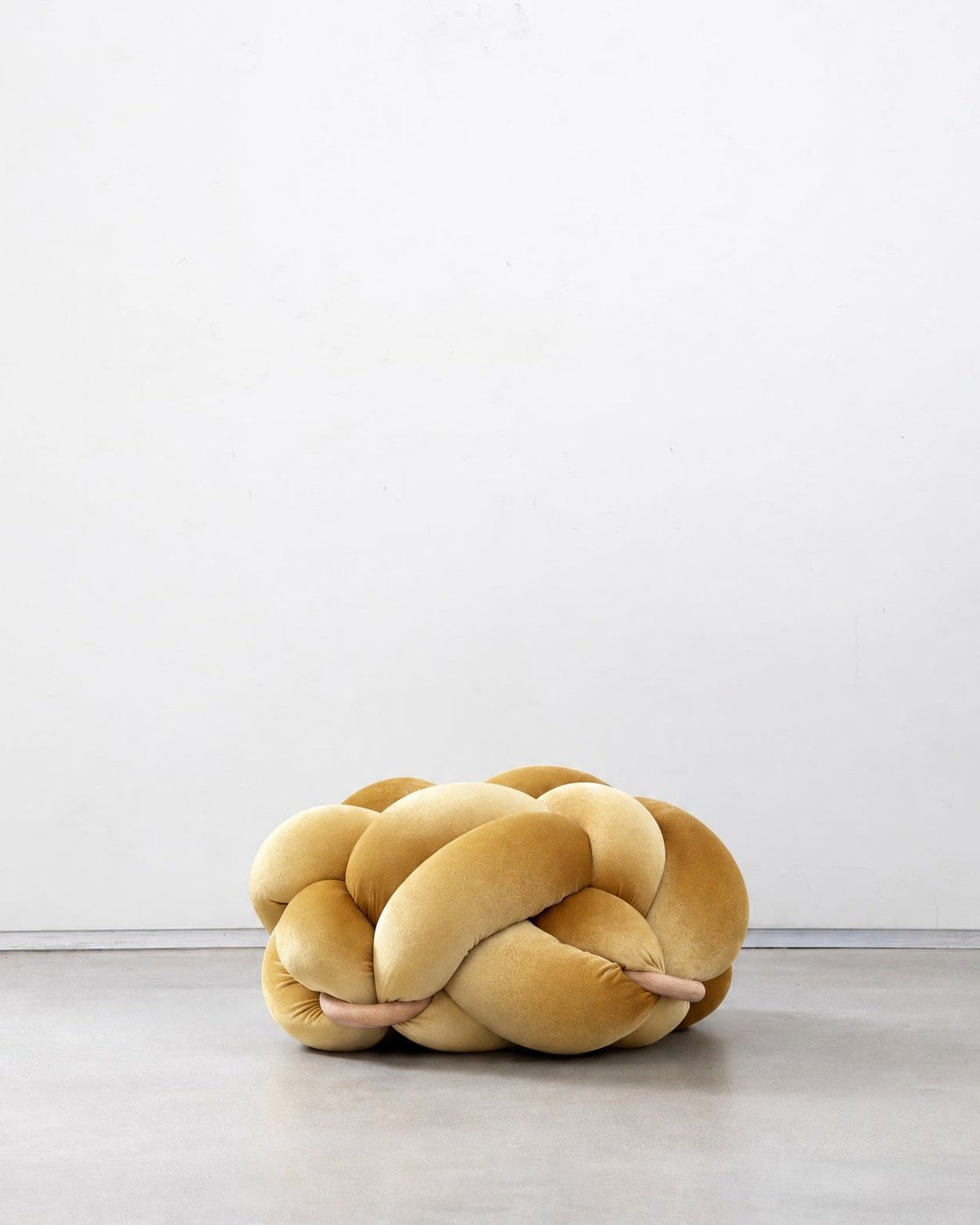 Sunlight yellow velvet knot ottoman on a concrete floor