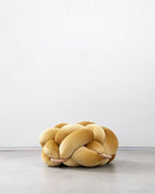 Sunlight yellow velvet knot ottoman on a concrete floor