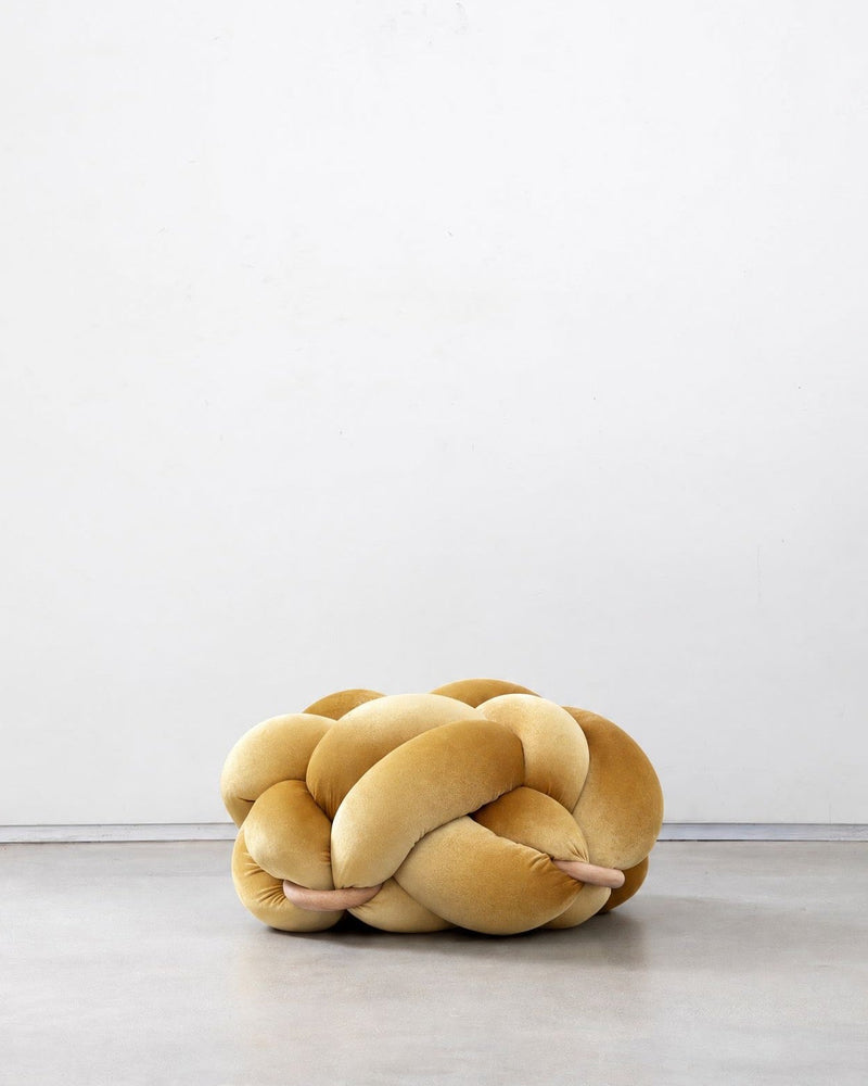 Sunlight yellow velvet knot ottoman on a concrete floor
