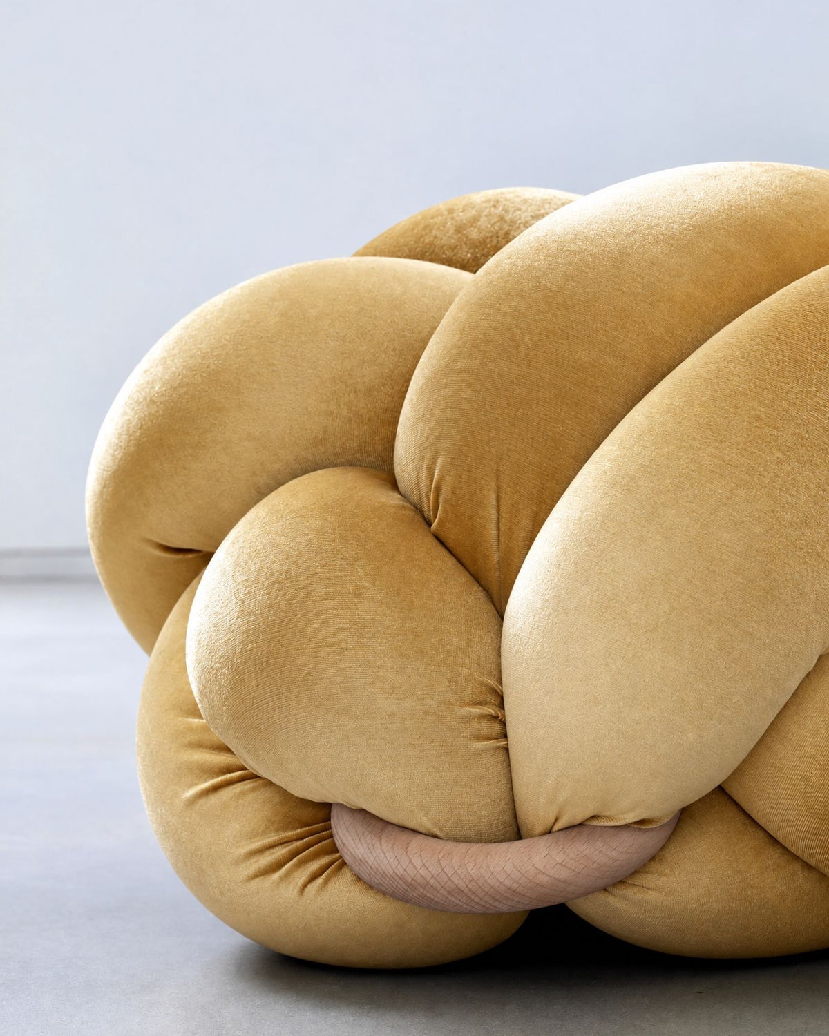 Close-up of a sunlight yellow velvet knot ottoman with its wooden ring