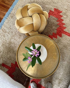Top view of a sunlight yellow velvet knot ottoman beside a brass side table