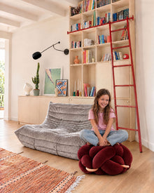 Girl sitting on the (M) Maroon Knot Ottoman