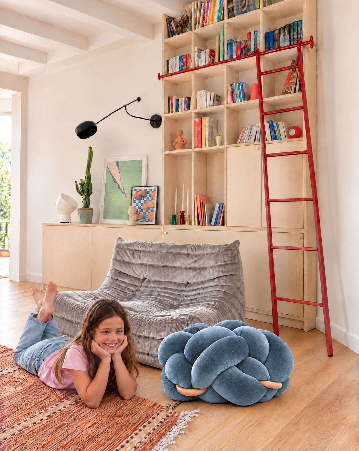 Girl on the rug next to the (M) Ocean Blue Knot Ottoman