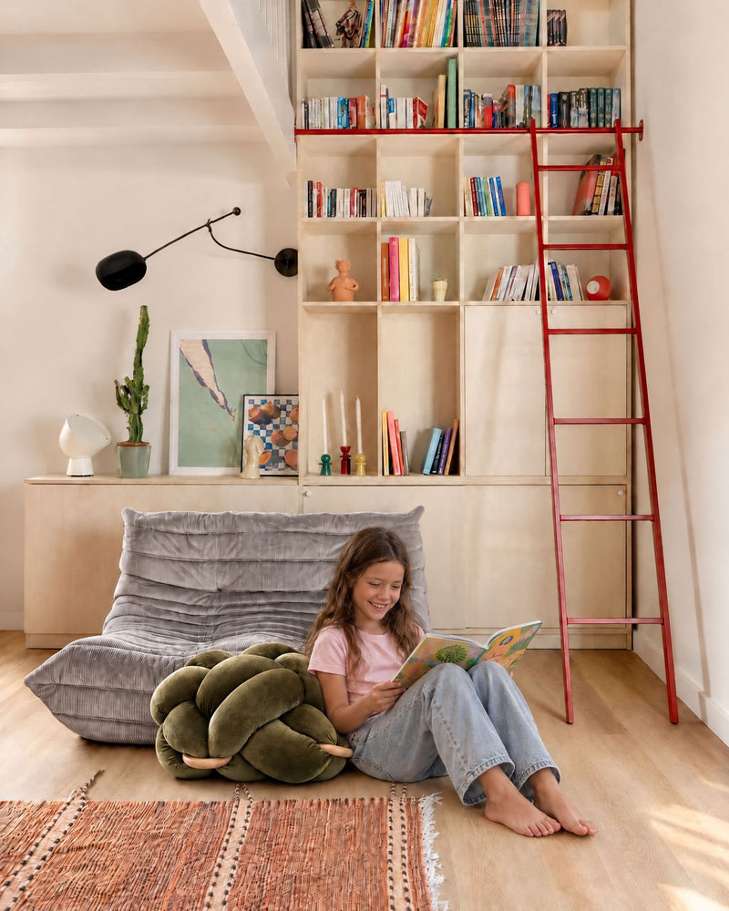 Girl reading next to the (M) Olive Green Knot Ottoman