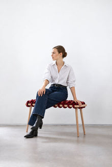 Woman sitting on a 37 inch burgundy velvet woven bench